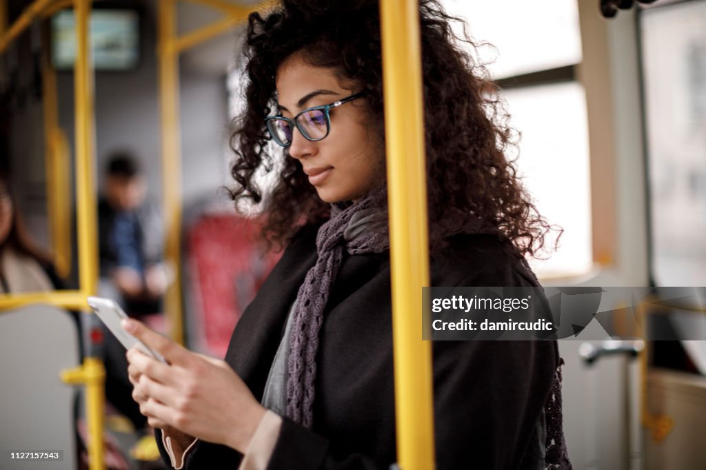 Junge Frau mit Bus und Smartphone unterwegs