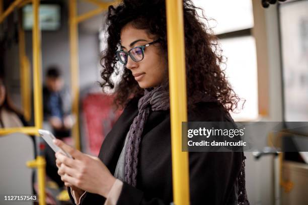 junge frau mit bus und smartphone unterwegs - öffentliches verkehrsmittel stock-fotos und bilder