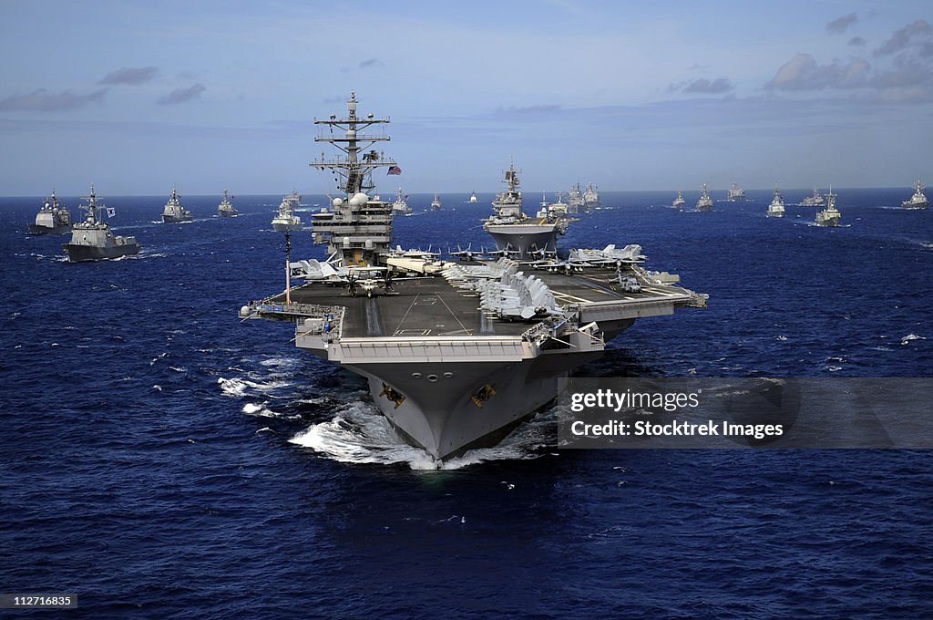 Aircraft carrier USS Ronald Reagan leads a mass formation of ships through the Pacific Ocean.