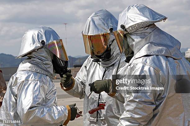 aircraft rescue firefighter marines look over each others bunker suits. - roupa a prova de fogo - fotografias e filmes do acervo