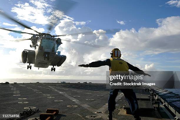 aviation boatswain's mate directs a ch-53e super stallion onto the flight deck of uss harpers ferry. - us navy stock pictures, royalty-free photos & images