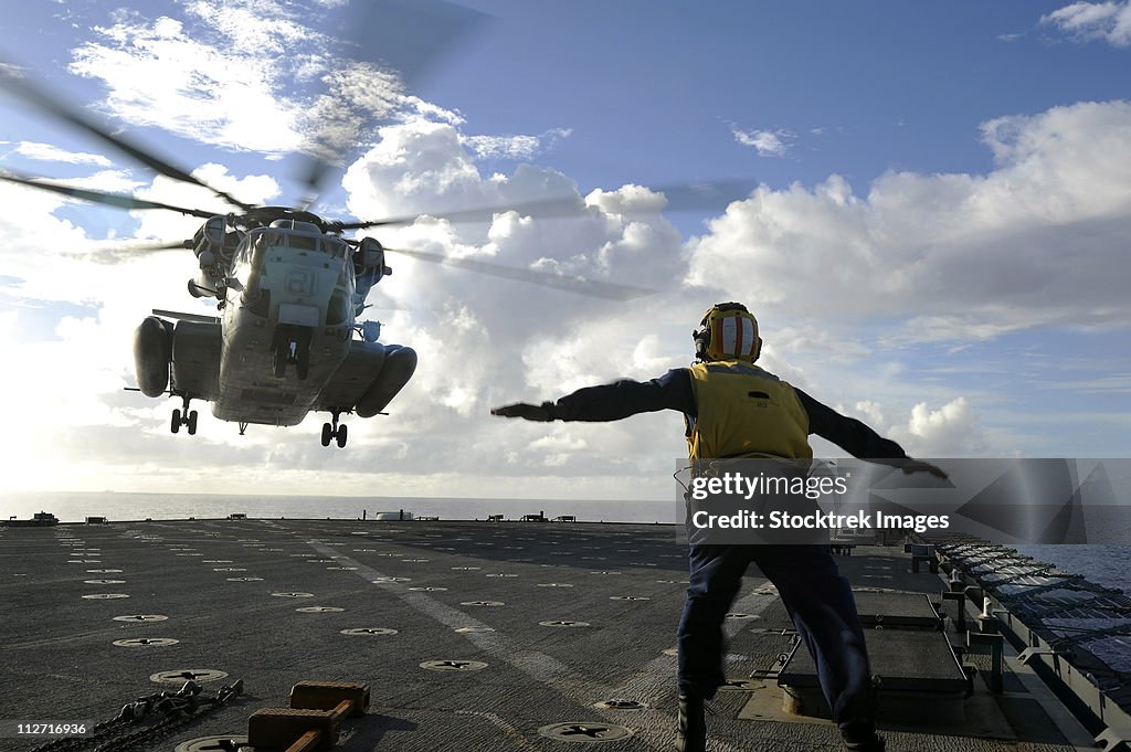 Aviation Boatswain's Mate directs a CH-53E Super Stallion onto the flight deck of USS Harpers Ferry.