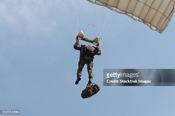a member of the british army pathfinder platoon prepares to land from a parachute jump. - fallen soldier 個照片及圖片檔
