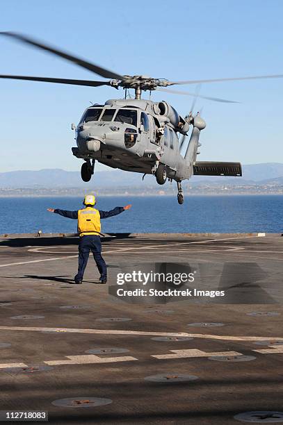 boatswains mate directs an mh-60s sea hawk helicopter on the flight deck of uss comstock - shiphawk stock pictures, royalty-free photos & images