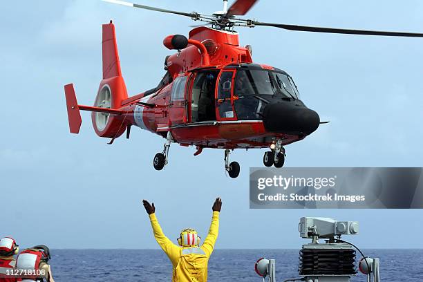 boatswain mate directs a hh-65a dolphin aboard the guided-missile destroyer uss russell. - police rescue stock pictures, royalty-free photos & images