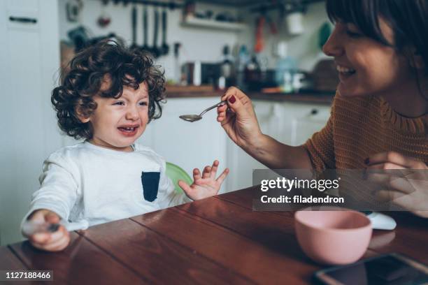 mother giving syrup to her son - hand over mouth stock pictures, royalty-free photos & images