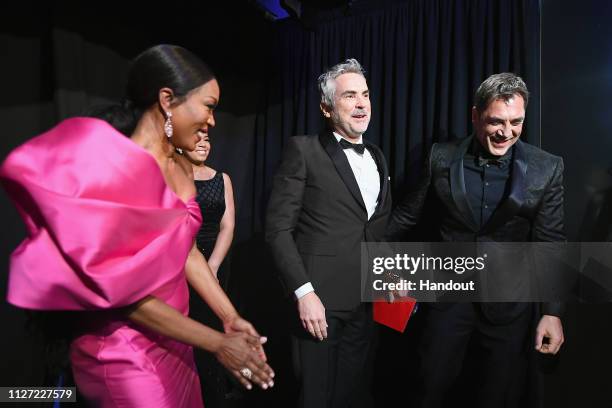 In this handout provided by A.M.P.A.S., presenter Angela Bassett poses with Foreign Language Film winner Alfonso Cuaron and presenter Javier Bardem...