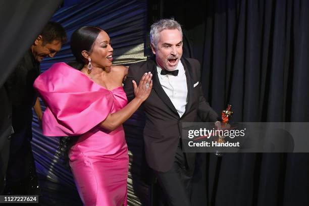 In this handout provided by A.M.P.A.S., presenter Angela Bassett poses with Best Foreign Language Film winner Alfonso Cuaron backstage during the...