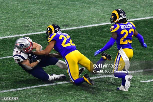 Marcus Peters and Nickell Robey-Coleman of the Los Angeles Rams tackle Rex Burkhead of the New England Patriots in the second half during Super Bowl...