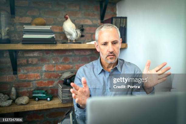 serious businessman video conferencing on computer - one man only business stock pictures, royalty-free photos & images