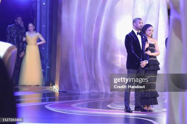 In this handout provided by A.M.P.A.S., Chadwick Boseman and Constance Wu look on backstage as presenters Michael B. Jordan and Tessa Thompson speak...