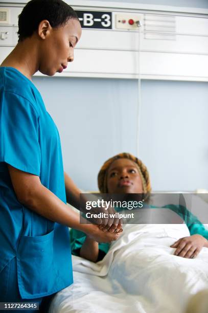 female doctor in medical scrubs attending to a patient in hospital looking down - patient lying down stock pictures, royalty-free photos & images