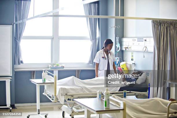 female doctor attending to a patient in a hospital ward - hospital bed with iv stock pictures, royalty-free photos & images