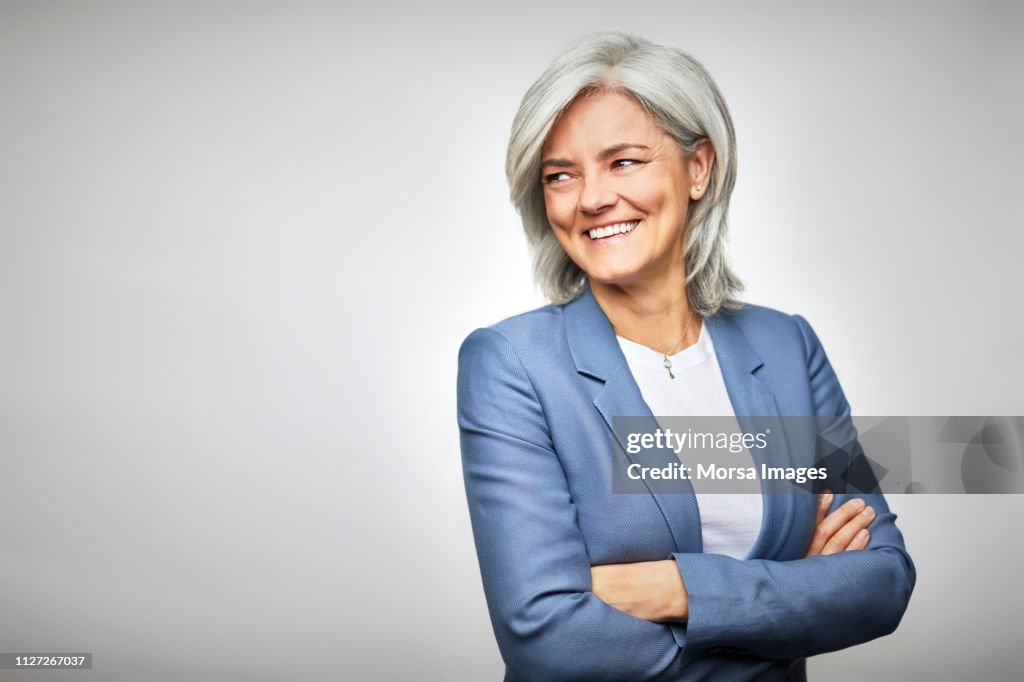 Happy businesswoman with arms crossed looking away