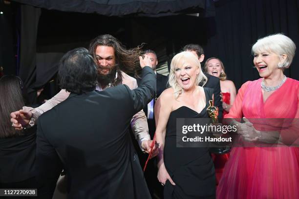 In this handout provided by A.M.P.A.S., Presenters Jason Momoa and Helen Mirren react backstage with director Jimmy Chin and producer Shannon Dill...