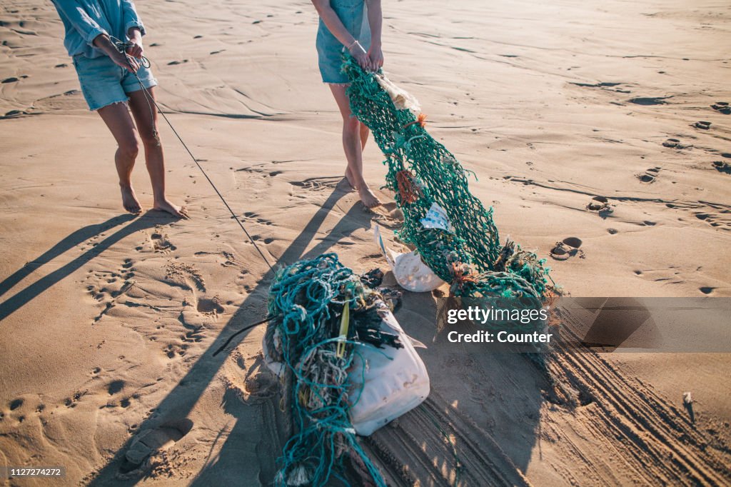 Two women collecting garbage on the beach
