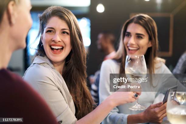 lachende vrouw holding wineglass door vrienden in bar - alleen jonge vrouwen stockfoto's en -beelden