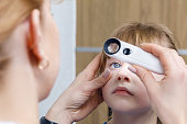 A closeup of an ophthalmologist checking the eye of a child.