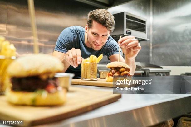 smiling chef serving burger and french fries - chef burger stock pictures, royalty-free photos & images