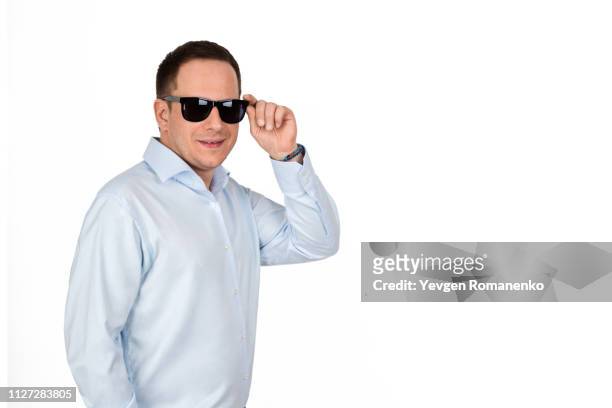 portrait of a young handsome businessman in formal shirt and pants posing in black sunglasses on white background - formal shirt stock pictures, royalty-free photos & images