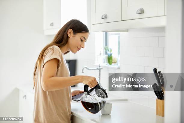 junge frau gießen kaffee in der tasse zu hause - woman drinking coffee at home stock-fotos und bilder