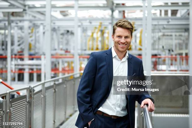 glimlachend mid volwassen zakenman permanent in fabriek - industrial portrait stockfoto's en -beelden