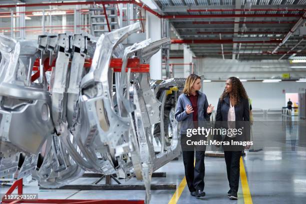 ingenieure gehen während der diskussion von auto-chassis - automobilindustrie stock-fotos und bilder