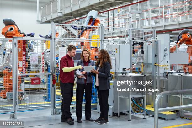 full length of engineers discussing in car plant - woman standing full length stock pictures, royalty-free photos & images