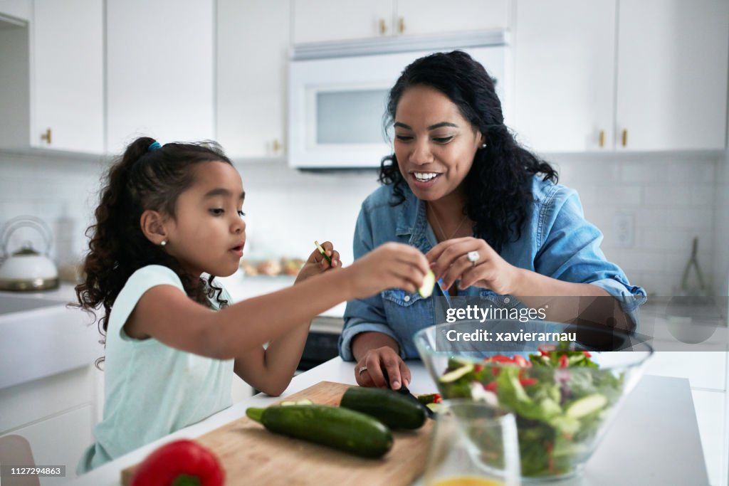 Girl learning to prepare meal from mother