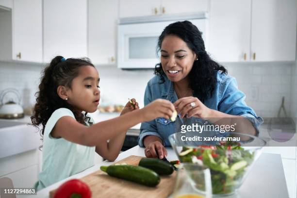 Girl learning to prepare meal from mother