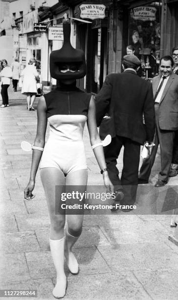 Le mannequin Valerie Saint-Helen présente un ensemble de bain vert et bleu-roi avec un casque spatial et des chaussettes vert pistache dans les rues...