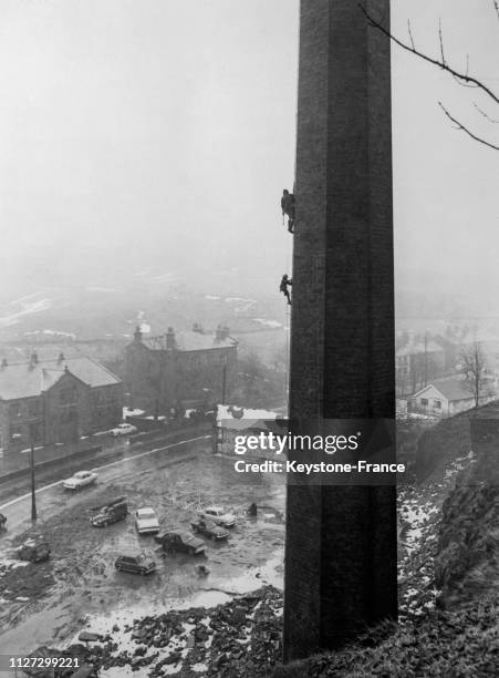 Arthur Clarkson et son fils Roy âgé de 7 ans, en cordée, escaladent une immense cheminée d'usine, au Royaume-Uni, en janvier 1968.