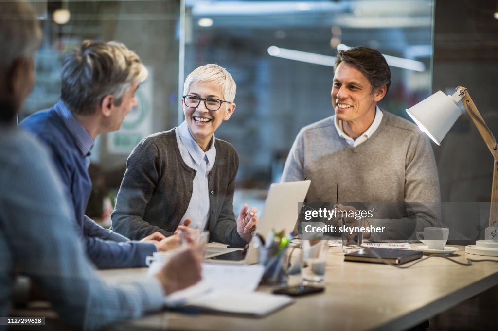 Happy mature businesswoman talking to her colleagues on a meeting in the office.