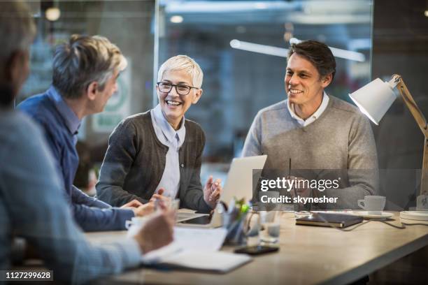 happy mature businesswoman talking to her colleagues on a meeting in the office. - smart casual laptop stock pictures, royalty-free photos & images