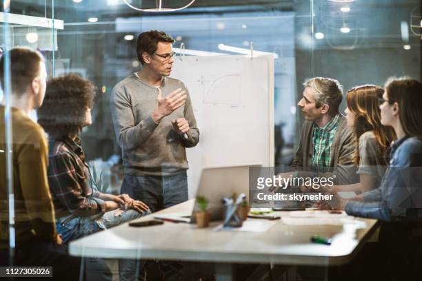 mid adult businessman talking to his colleagues on presentation in the office. - corporate training stock pictures, royalty-free photos & images