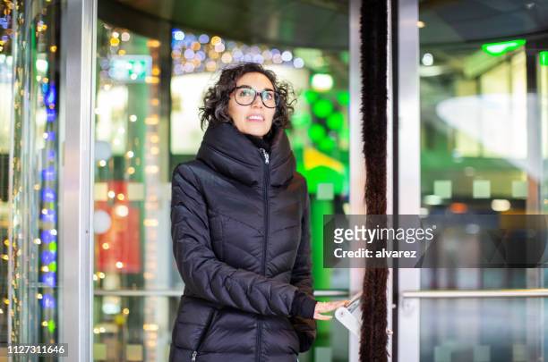 mature woman walking out of a building - overcoat stock pictures, royalty-free photos & images