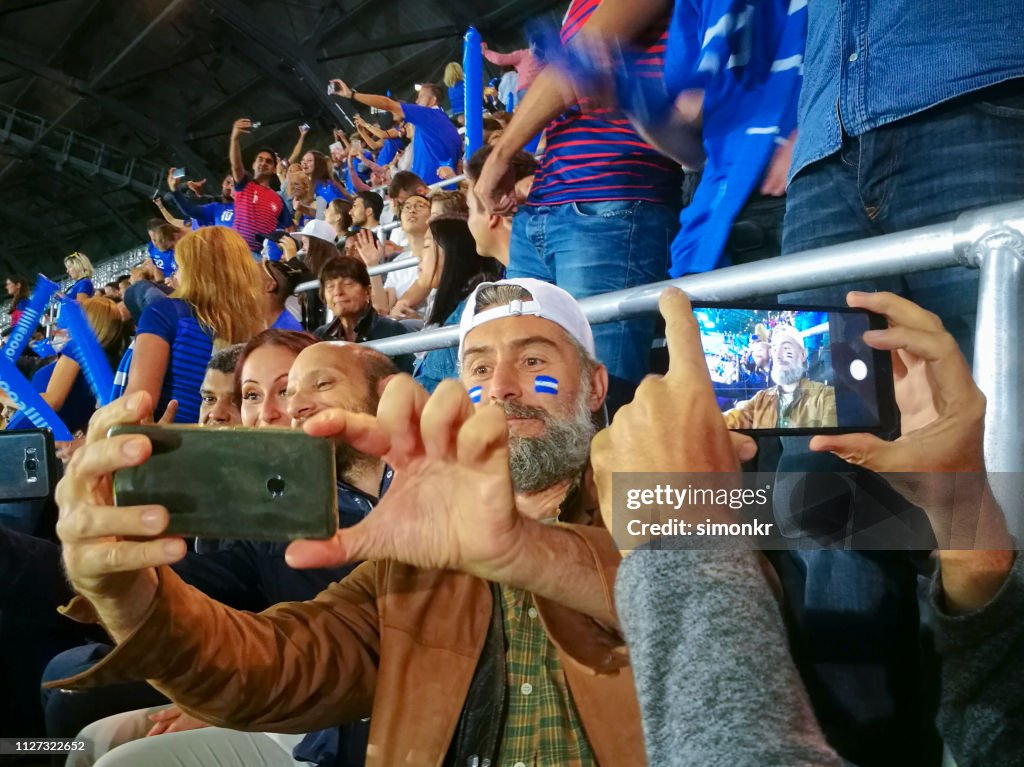 Spectators taking selfie in stadium