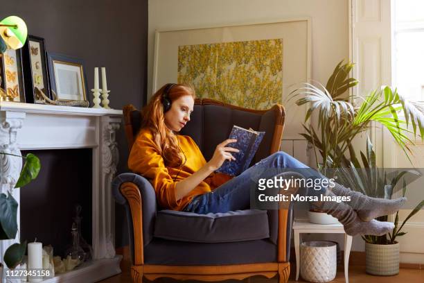 mujer leyendo un libro mientras escucha música - reading fotografías e imágenes de stock