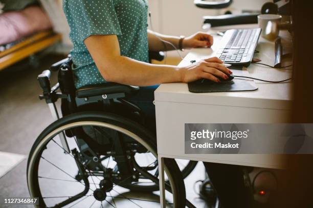 midsection of young disabled woman using computer at home - körperliche behinderung stock-fotos und bilder