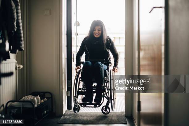 Full length of smiling young disabled woman entering home