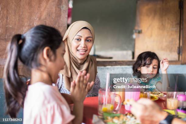 asian mother with her family at lunch, watches her daughter clapping her hands - kid eating restaurant stock pictures, royalty-free photos & images