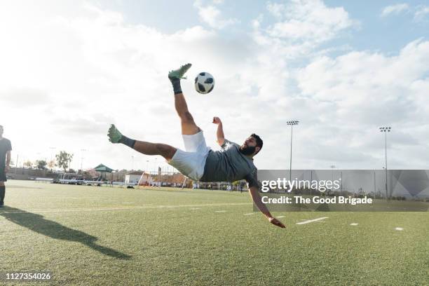 soccer player kicking ball in mid air - middle age imagens e fotografias de stock