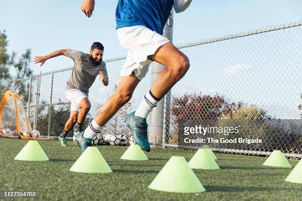 soccer players performing warm up drills on field - football training stock-fotos und bilder