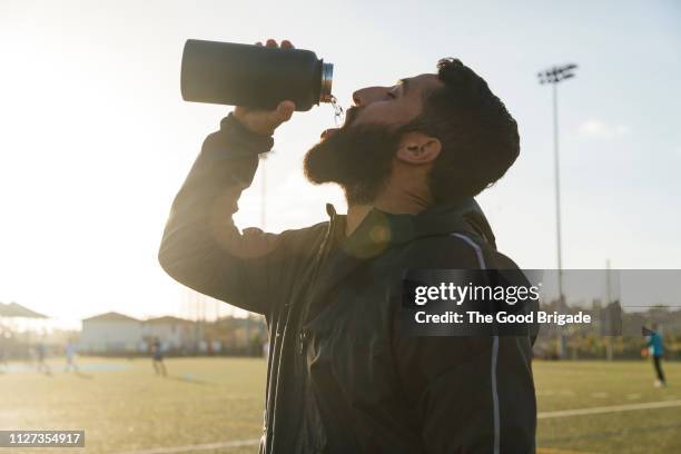 male athlete drinking from water bottle on sports field - drinking from bottle stock pictures, royalty-free photos & images