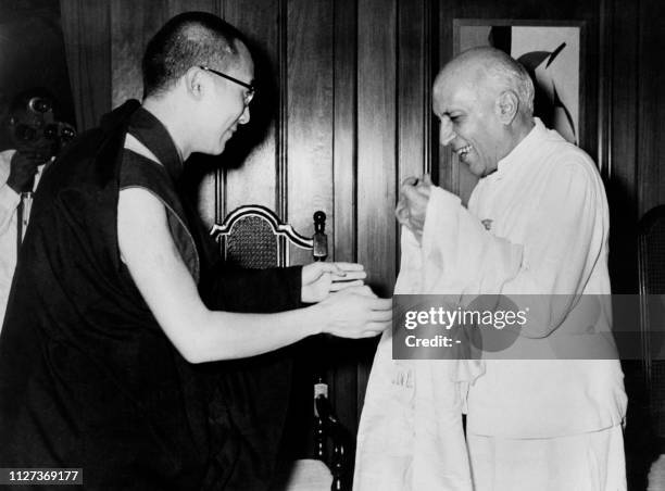 Dalai Lama L, traditional religious and temporal head of Tibet's Buddhist clergy, offers a traditional Tibetan white sash on September 7, 1959 in New...