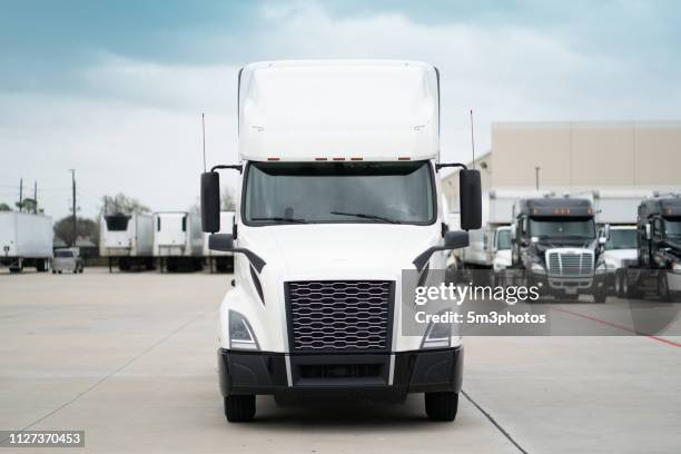 white 18 wheeler semi-truck parked in a yard with a fleet of trucks - camion blanc photos et images de collection