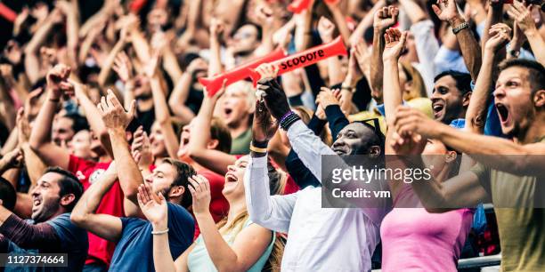 folla che tifa per la loro squadra con le braccia alzate - avvenimento sportivo foto e immagini stock
