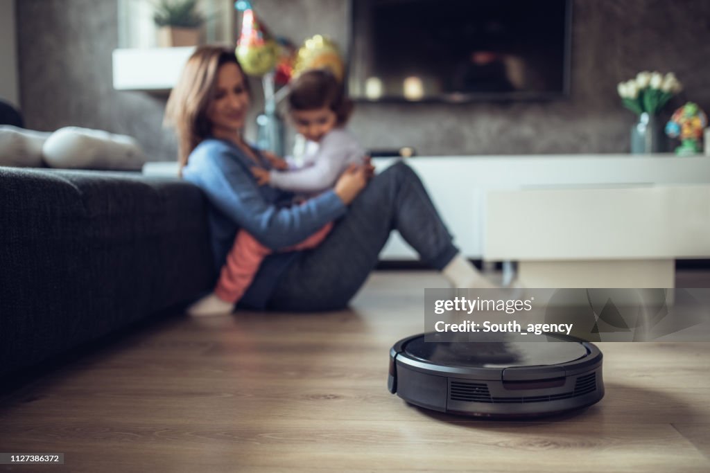 Roboter-Staubsauger reinigen, während Mutter und Tochter spielen