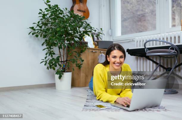 woman using laptop and relaxing at home - yellow carpet stock pictures, royalty-free photos & images