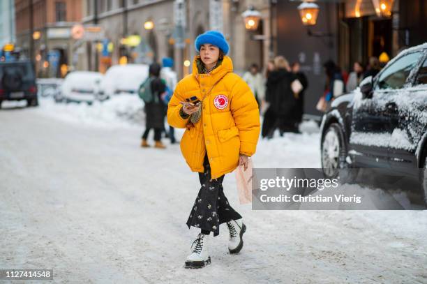 Guest is seen wearing Dior saddle bag, yellow puffer down feather coat Acne, blue beanie, flared cropped pants, white boots outside Ida Sjöstedt...